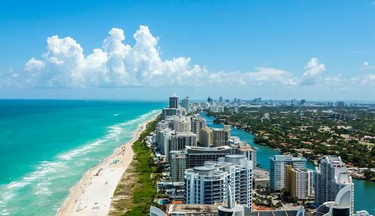 Vibrant Miami skyline at sunset, featuring iconic high-rise buildings, palm trees, and the sparkling waters of Biscayne Bay